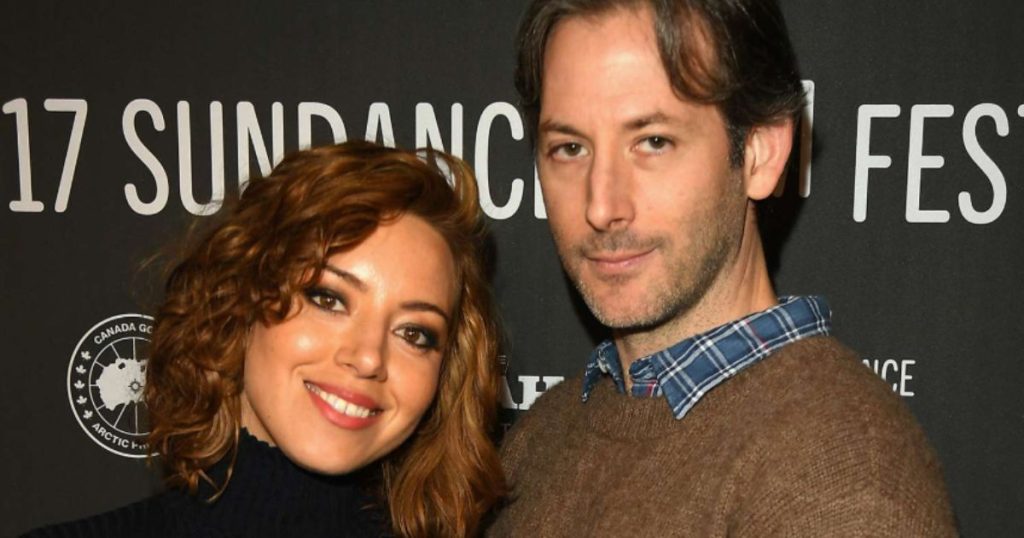 Aubrey Plaza on a podcast set, speaking into a mic with a thoughtful expression