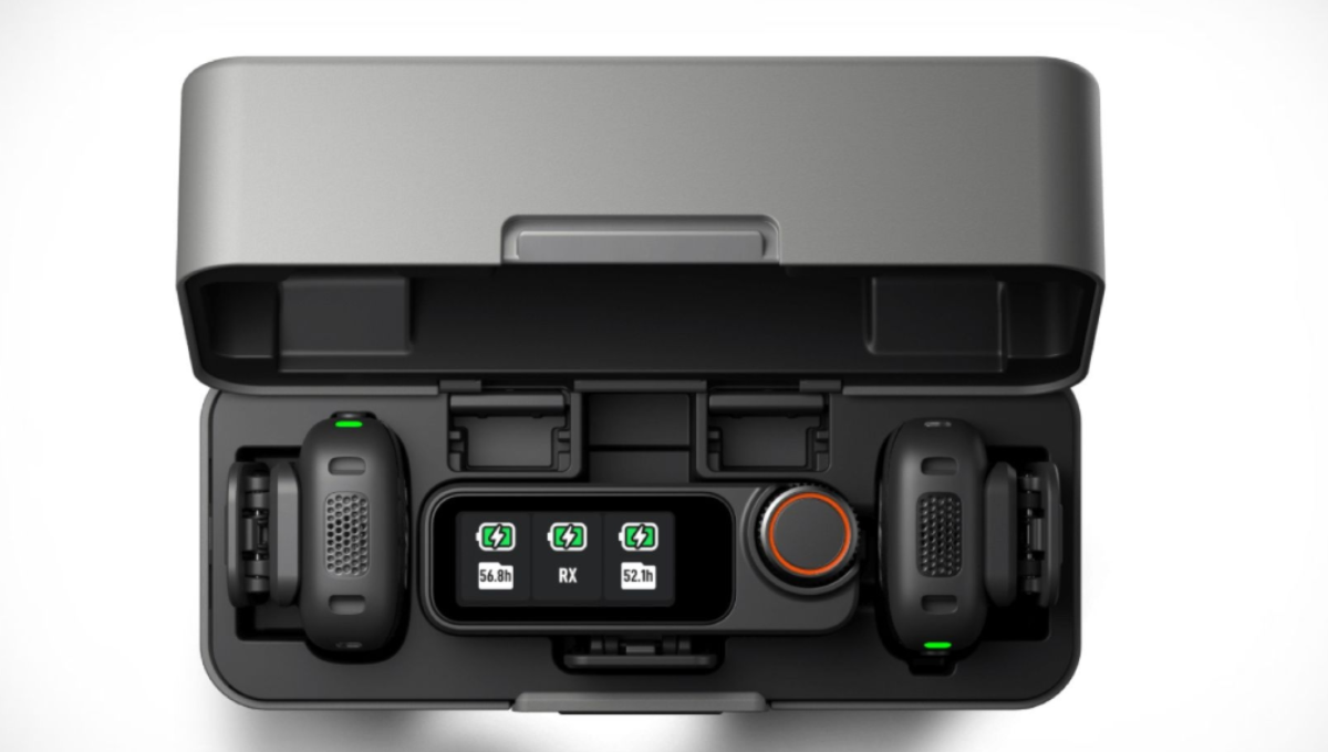 DJI Mic 3 transmitter, receiver, and charging case on a desk with camera gear in the background