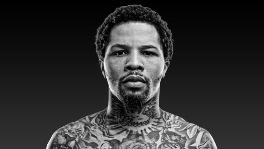 Gervonta “Tank” Davis in black trunks launching a left uppercut under arena lights