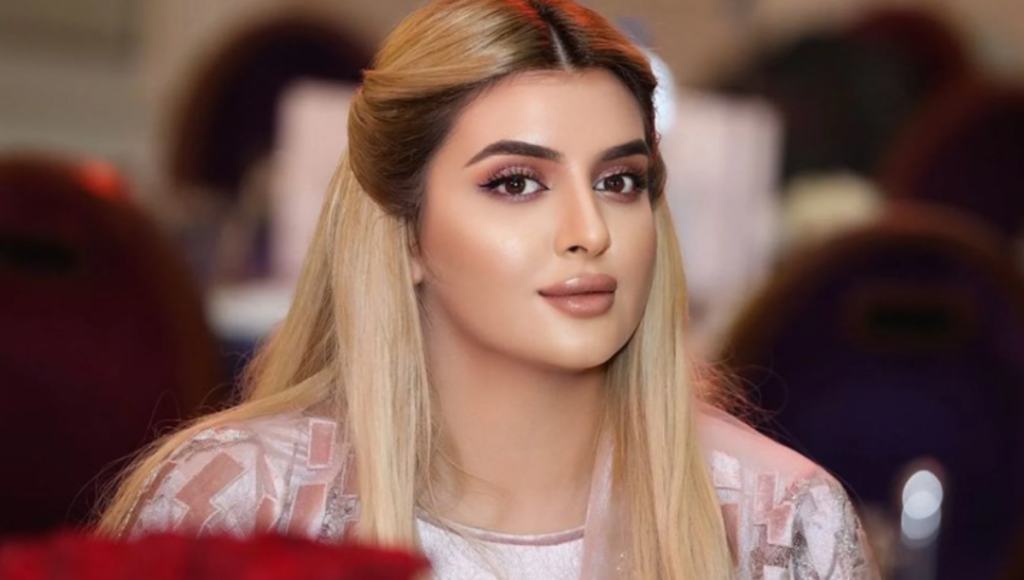 Sheikha Mahra at a fashion event, photographed in a gold-toned dress with a soft spotlight