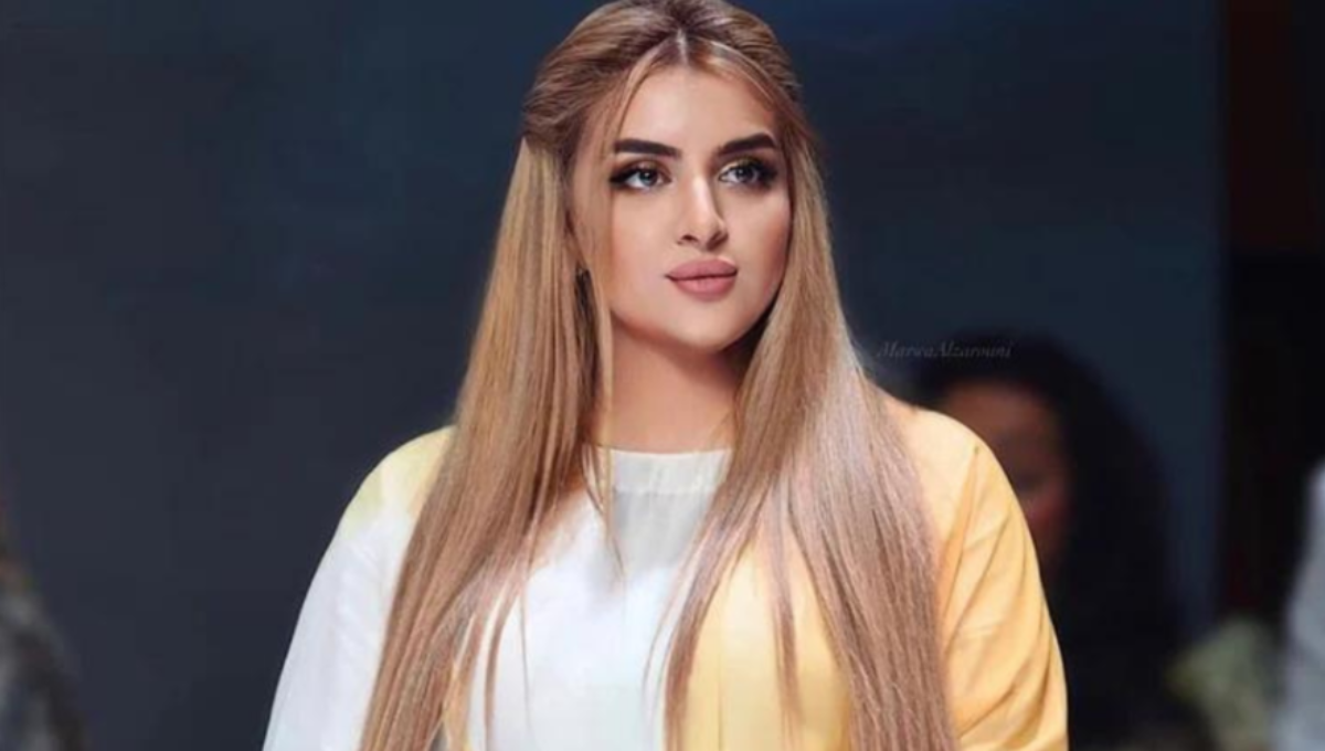 Sheikha Mahra at a fashion event, photographed in a gold-toned dress with a soft spotlight
