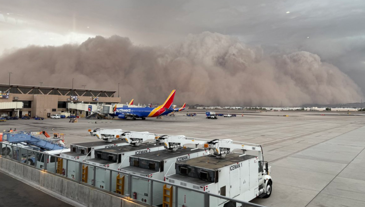 Towering wall of dust rolling over Phoenix Sky Harbor as aircraft and terminals disappear into brown haze