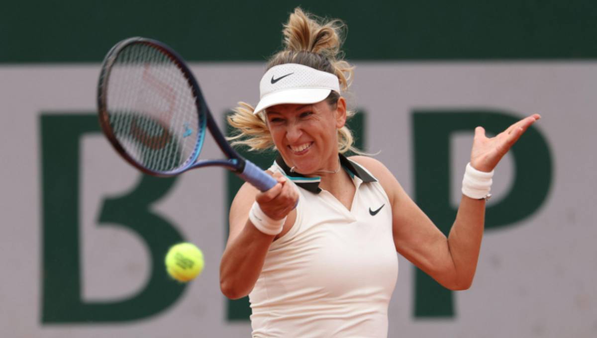 Victoria Azarenka fist pumps on a hard court after winning a US Open match under bright lights