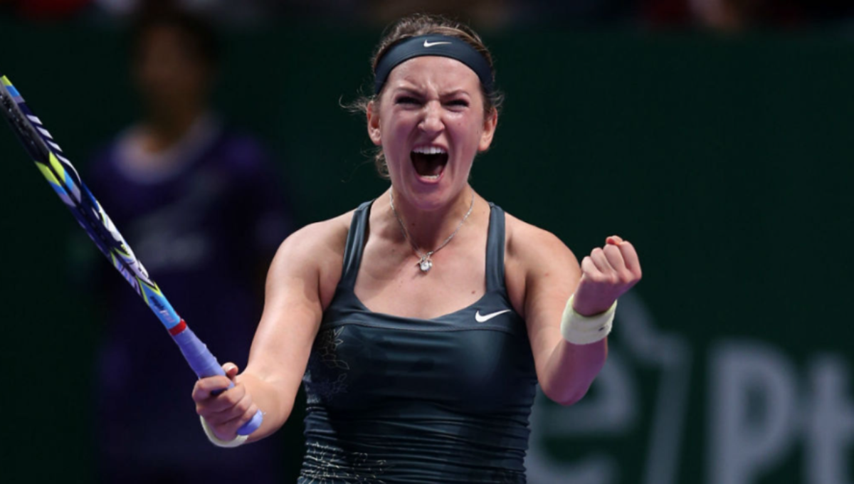 Victoria Azarenka fist pumps on a hard court after winning a US Open match under bright lights