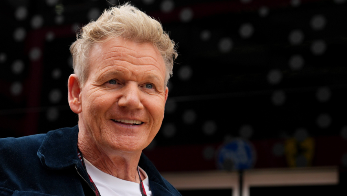 Gordon Ramsay smiling at a TV set kitchen, with soft lighting on his face