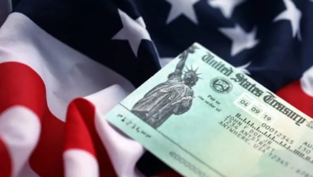 Close-up of an IRS envelope and a Treasury check on a wood desk