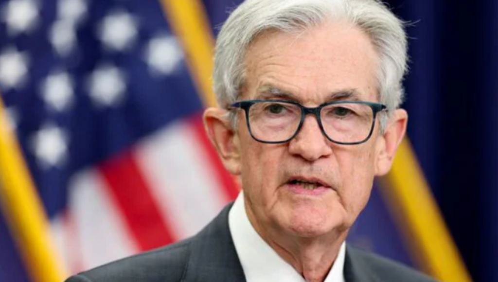 Federal Reserve Chair Jerome Powell speaking at a podium with Jackson Hole mountains in the background