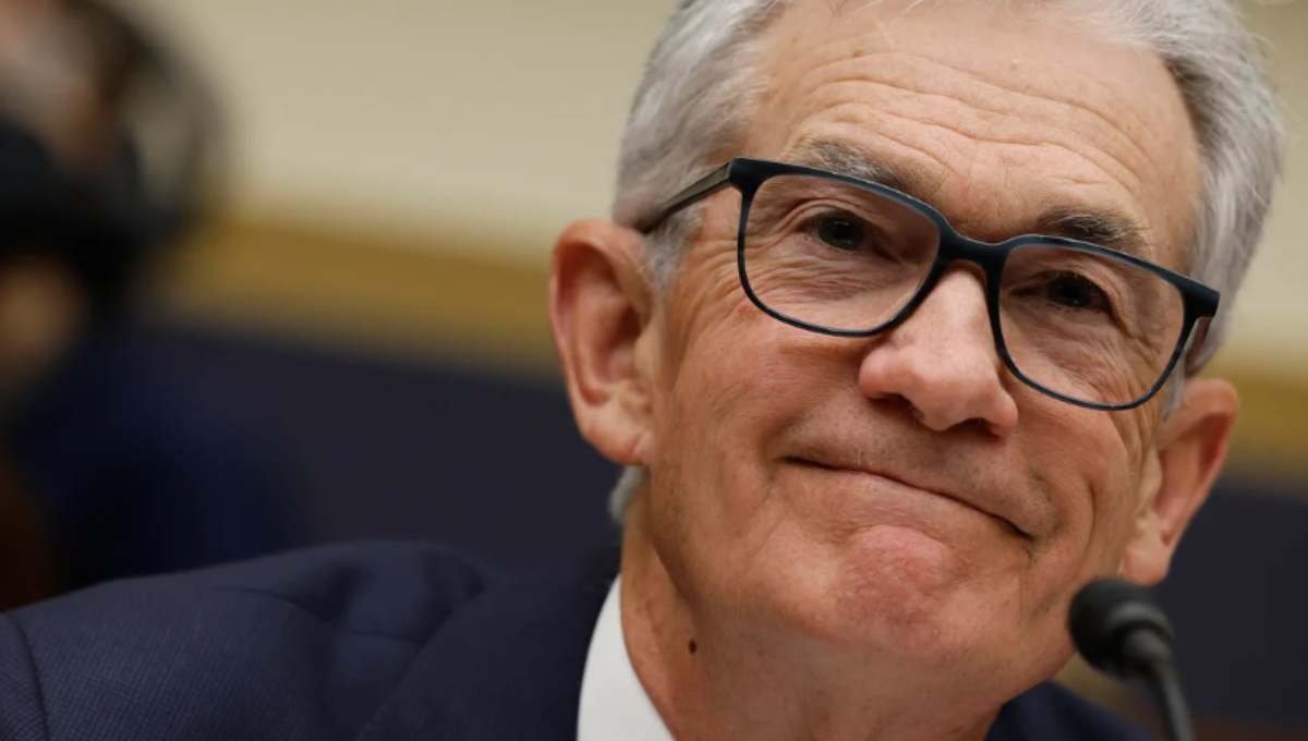 Federal Reserve Chair Jerome Powell speaking at a podium with Jackson Hole mountains in the background