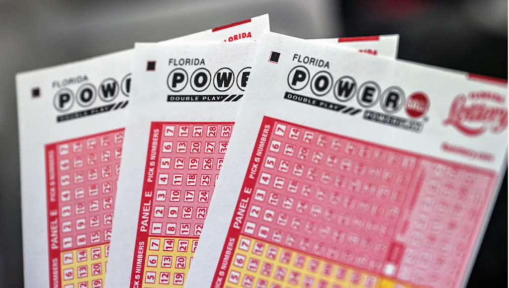 Powerball play slip and red lottery ball on a counter with a pen