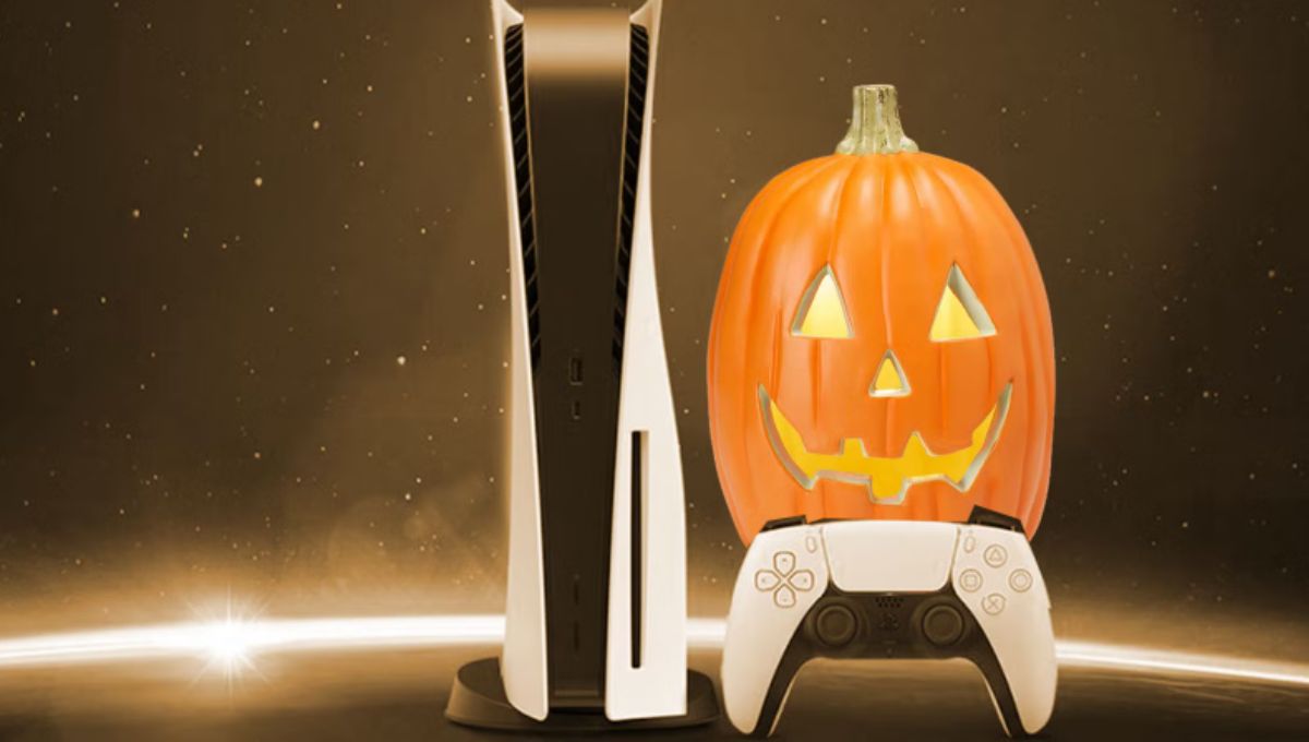 A DualSense controller lit by orange and purple Halloween lights next to a PS5 console