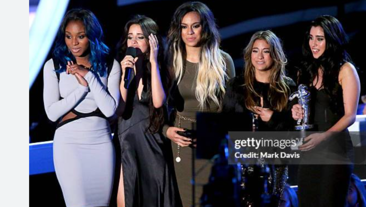 Fifth Harmony members on stage in coordinated black outfits performing under spotlights