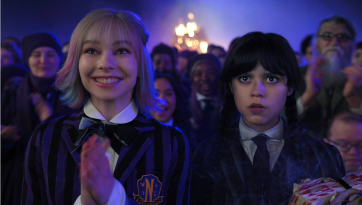 Jenna Ortega as Wednesday Addams staring forward in a gothic academy hallway, symbolic of a new season