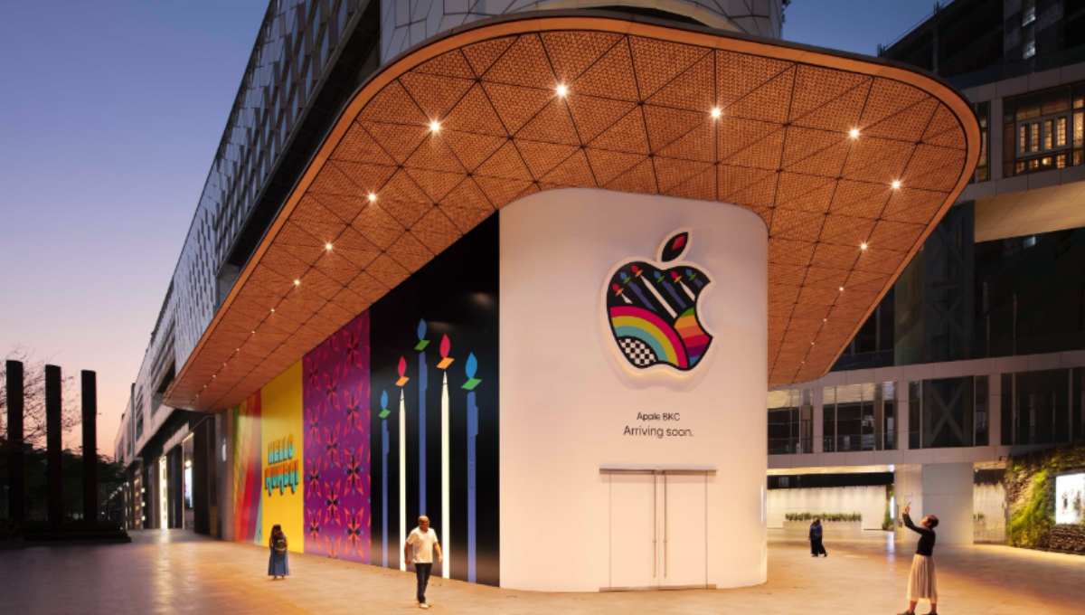 Exterior of a modern Apple Store with glass facade and customers gathering outside at dusk