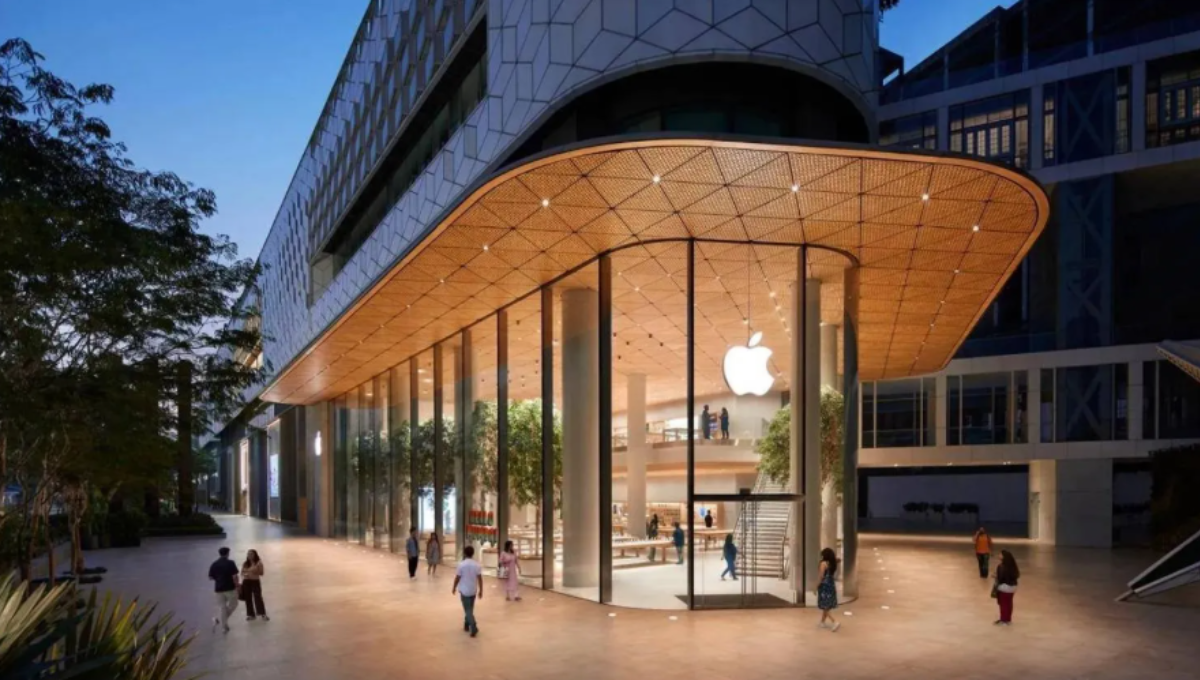 Exterior of a modern Apple Store with glass facade and customers gathering outside at dusk