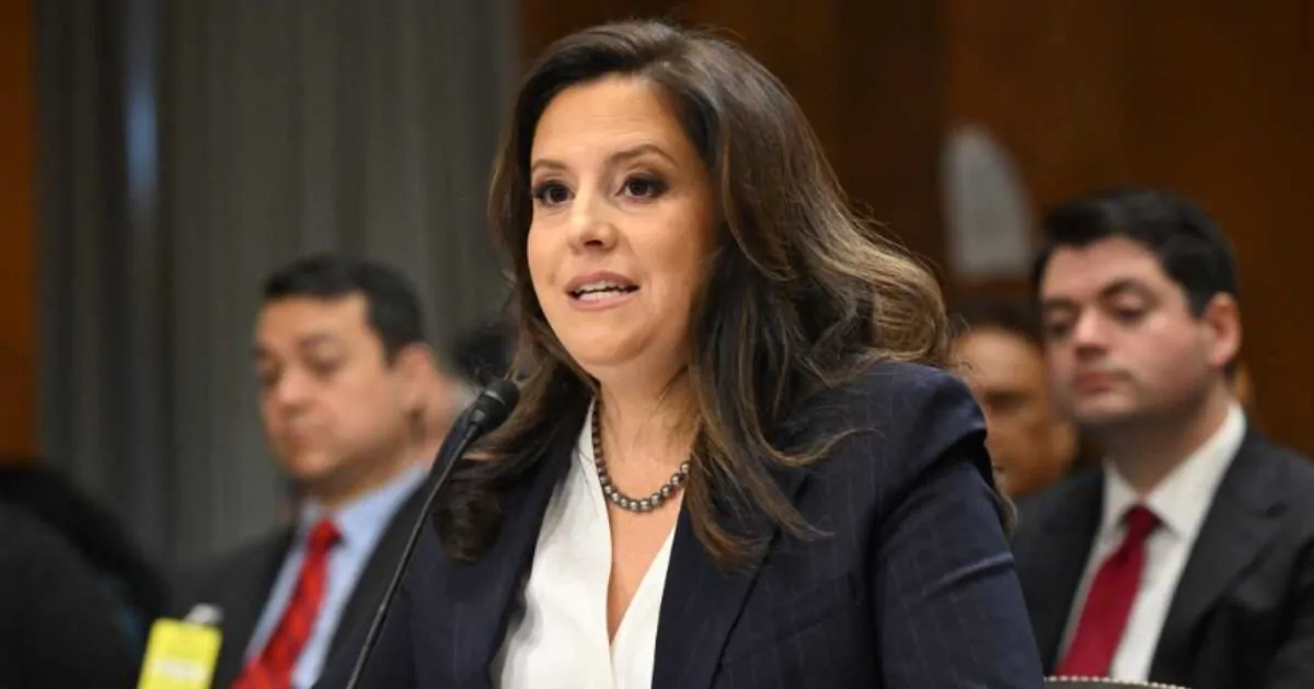 Elise Stefanik speaking at a podium with U.S. flags in the background during a New York event